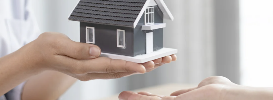 An agent holding a small replica of a home in her palm